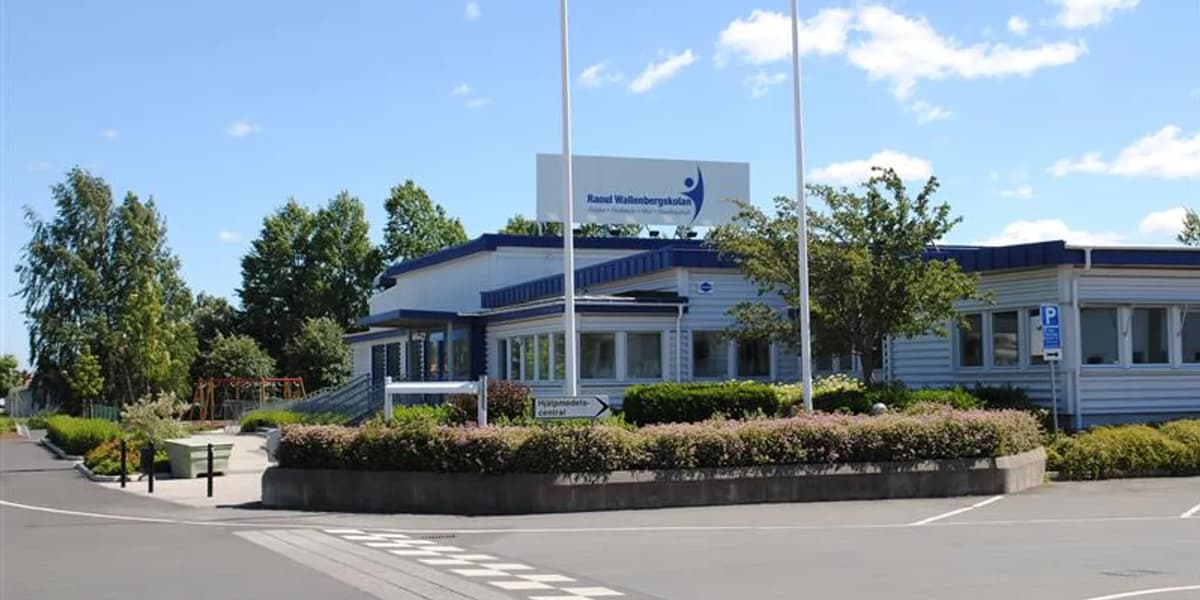 Vit skolbyggnad i en vägkorsning