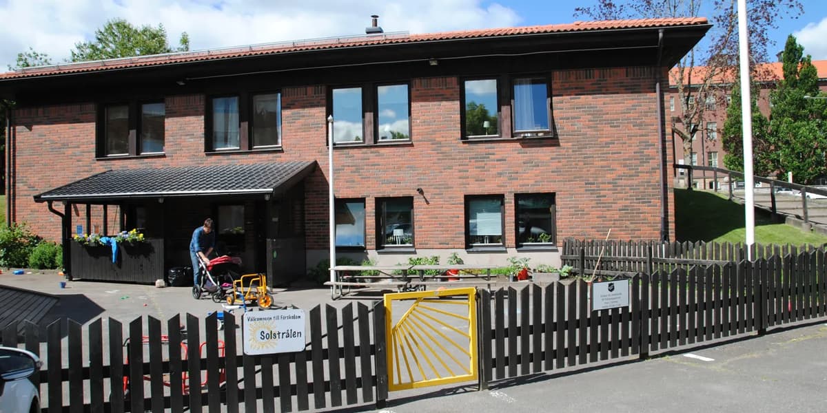 En tegelbyggnad med ett svart staket runt
