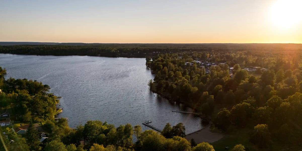Solen går ner över en sjö omgiven av träd.