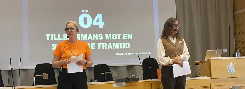 Två kvinnor står framför presentation om samarbetet