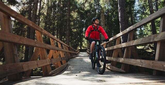 En man cyklar i skogen.