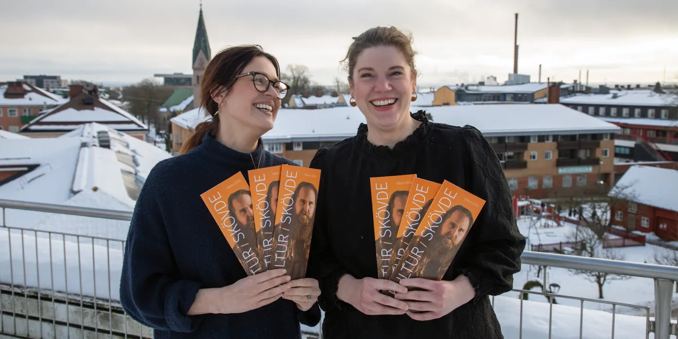 Två personer som håller i broschyrer.