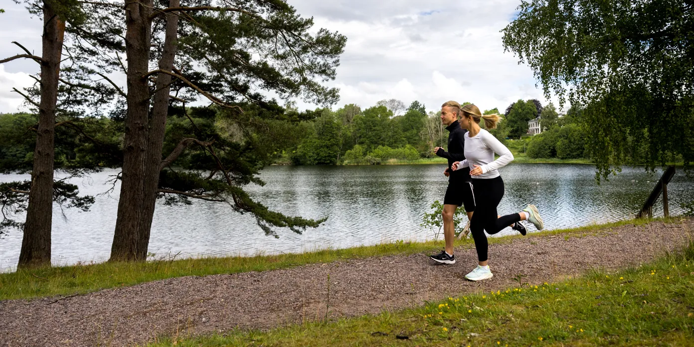 Två personer som springer vid en sjö.
