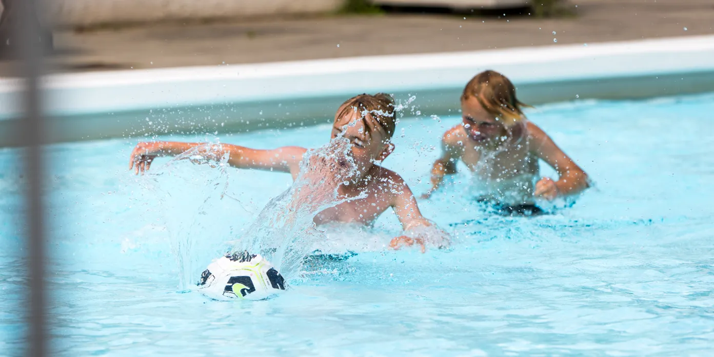Två pojkar som leker med en boll i vattnet på Billingebadet.