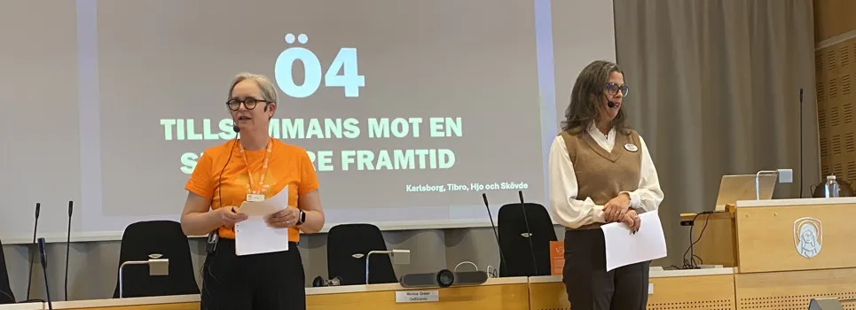 Två kvinnor står framför presentation om samarbetet