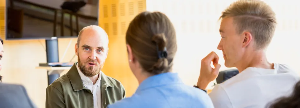 Bild på tre personer som sitter och pratar med varandra.